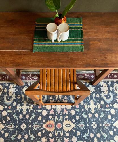 a wooden coffee table with two mugs and a bench at Alpas Siargao in General Luna