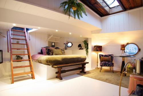 een slaapkamer met een bed, een ladder en een stoel bij Najade Eco Houseboat in Amsterdam
