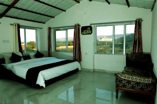 a bedroom with a king sized bed and windows at The Forest View Resort in Khilchipur