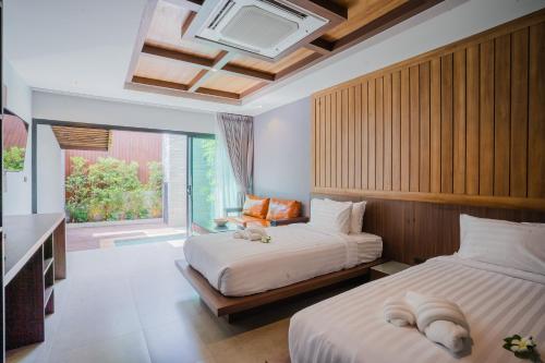 two beds in a hotel room with a window at Malabar Pool Villa Phuket in Phuket Town