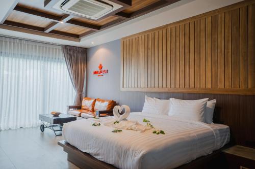 a hotel room with a large bed and a chair at Malabar Pool Villa Phuket in Phuket Town