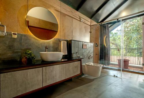 La salle de bains est pourvue d'un lavabo, de toilettes et d'un miroir. dans l'établissement Crystal Kuruva Nature Resort & Spa, à Wayanad
