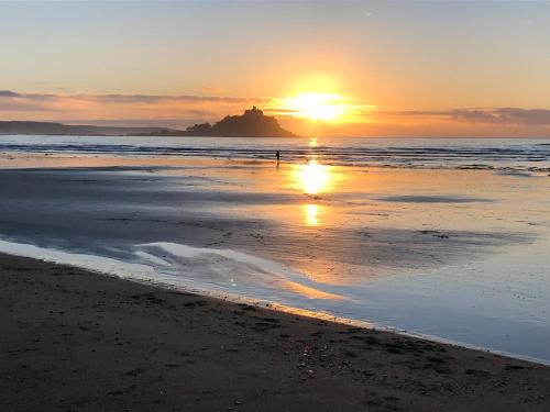 a person walking on the beach at sunset at Stylish Sea View Apartment with Parking in Penzance