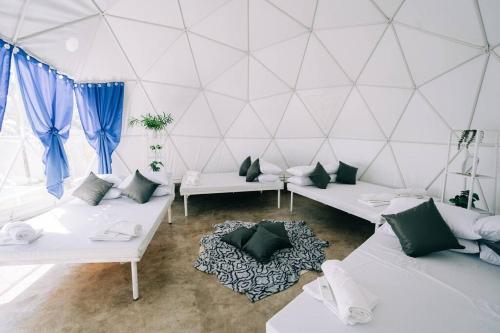 Habitación con sofás blancos y cortinas azules. en Family Getaway Dome Glamping w/ Private Hotspring, en Lubo