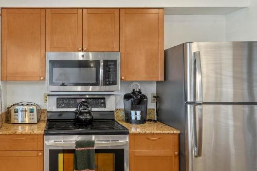 eine Küche mit einem Herd, einer Mikrowelle und einem Kühlschrank in der Unterkunft Sandpiper 216A condo in Princeville