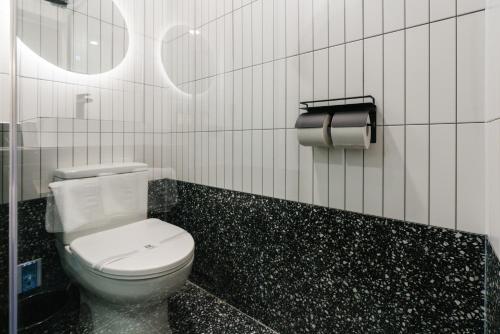 a bathroom with a white toilet and a black tile wall at Yangju Hotel Ippda in Yangju