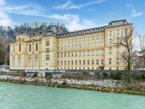 a large yellow building next to a river at Holiday Home Feldkirch Panoramic Views in Feldkirch