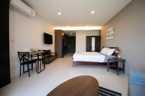a bedroom with a bed and a table and a desk at Escape Condominiums Beachfront Suites - Mae Phim in Rayong