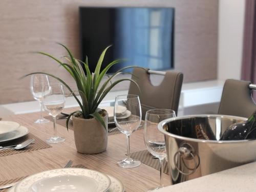Vila Ključe Apartments في بليد: طاولة مع كؤوس للنبيذ ونبات الفخار عليها