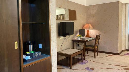 a hotel room with a desk and a table with a television at Oriental Silk Hotel in Guangzhou