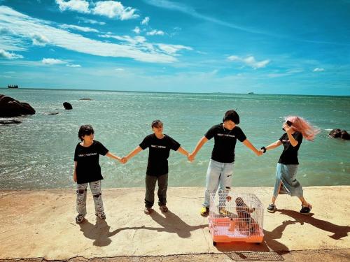 a group of people holding hands on the beach at Mũi Dinh Hotel in Phan Rang