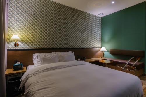 a bedroom with a large bed and a green wall at Yangju Hotel Ippda in Yangju