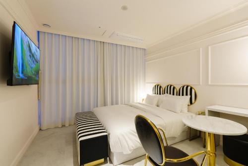 Schlafzimmer mit einem Bett, einem Tisch und einem TV in der Unterkunft Yangju Hotel Ippda in Yangju