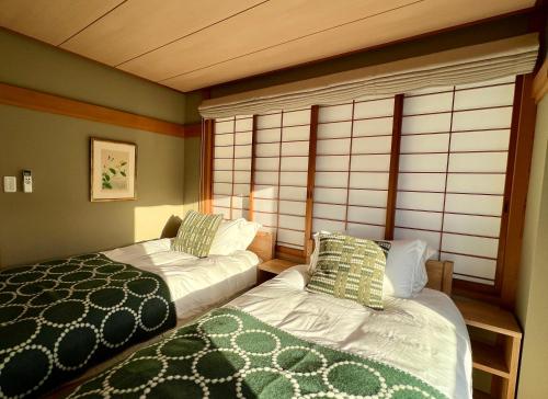 a bedroom with two beds and a window at Kihachikan South Nozawa Onsen in Nozawa Onsen