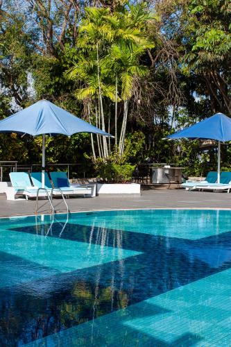 a swimming pool with two chairs and umbrellas at Airways Hotel in Port Moresby