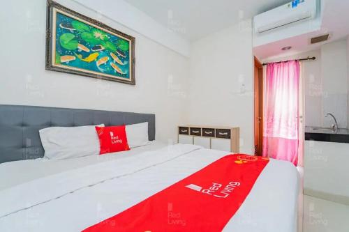 a bedroom with a bed with a red blanket at RedLiving Apartemen Green Lake View Cimanggis - WIN Property in Depok