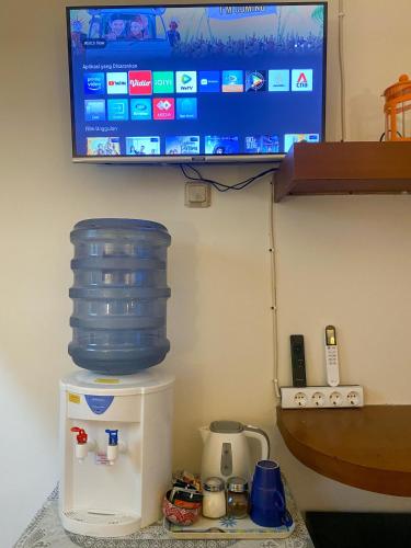 a tv on a wall with a water container on top of a refrigerator at Studio 62 in Depok