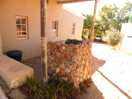 a stone retaining wall in front of a house at De Rusty Farm in De Rust