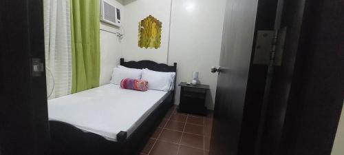 ein kleines Schlafzimmer mit einem Bett und einem grünen Vorhang in der Unterkunft Rochester Condo in Manila