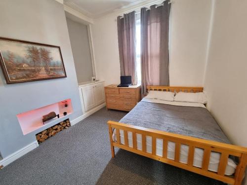 a bedroom with a wooden bed and a window at Cheerful 4 bedroom close to Uclan, Preston City Center in Preston