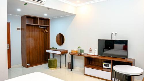 a living room with a television and a desk with a stool at Solo Grand City in Lawean