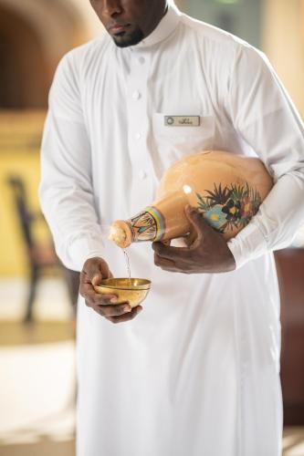 a man in a kitchen holding a mixing bowl at Anjum Makkah Hotel in Makkah