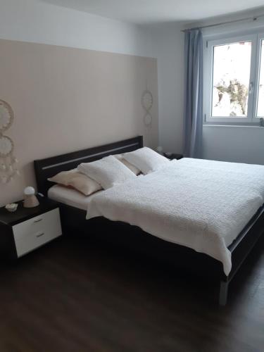 een slaapkamer met een bed met witte lakens en een raam bij Appartement FreiRaum in Sankt Martin am Tennengebirge