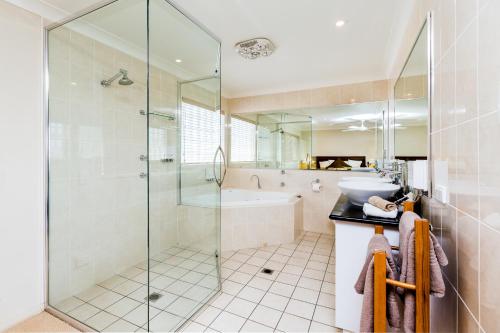 a bathroom with a shower and a sink and a tub at Soldiers Motel in Mudgee