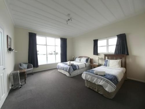 a bedroom with two beds and two windows at Pakington Ensuite homestay in Westport