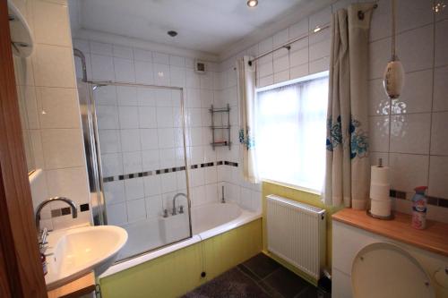 een badkamer met een bad, een wastafel en een douche bij Oaks House in Hanworth