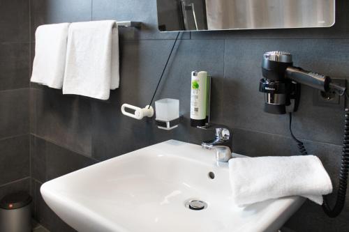 a bathroom with a white sink and a mirror and towels at ING Hotel by WMM Hotels in Ingolstadt