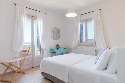 een witte slaapkamer met een bed en een raam bij Little Bird Lesvos in Petra