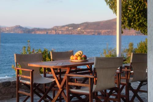 a wooden table with chairs and a bowl of fruit at Little Bird Lesvos in Petra