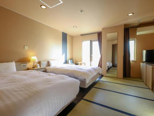 a hotel room with two beds and a television at Dormy Inn EXPRESS Asakusa in Tokyo