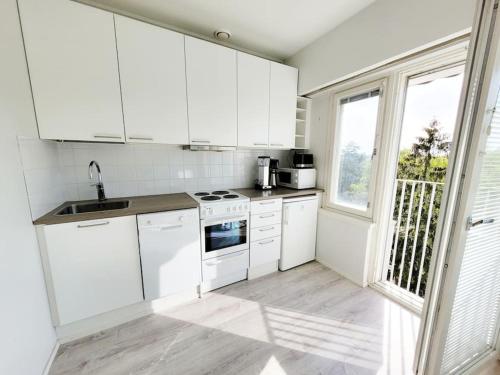 a white kitchen with white appliances and a window at TapiolaSky: airy, bright, great bed and spacious - close to Aalto campus and Tapiola center in Espoo