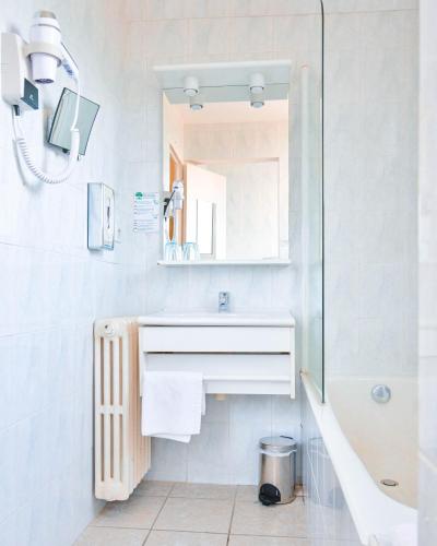 a white bathroom with a sink and a mirror at The Originals Boutique, Hôtel du Pont Roupt, Mende in Mende