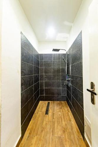 a bathroom with a shower with black tiles at Douala-Bonapriso, Bel Appartement in Douala