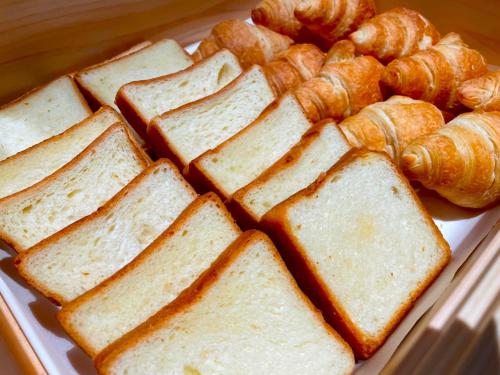 a white plate with bread and croissants and buns at Dormy Inn EXPRESS Asakusa in Tokyo