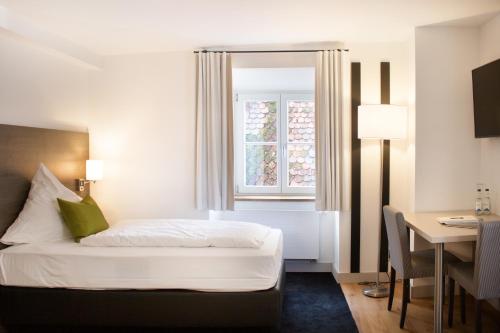 a bedroom with a bed and a desk and a window at MO Hotel by WMM Hotels in Ingolstadt