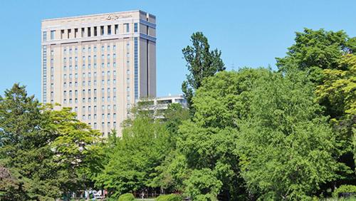 札幌市にあるホテルライフォート札幌の木立の前の高層ビル