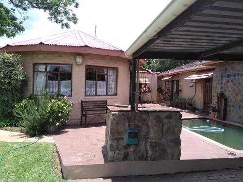 a house with a stone fireplace next to a pool at Khokha Moya Guesthouse in Ermelo