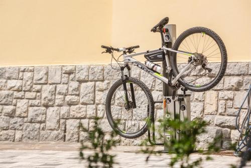 a bike parked on a pole in front of a wall at Al Lago Camping & Rooms in Riva del Garda