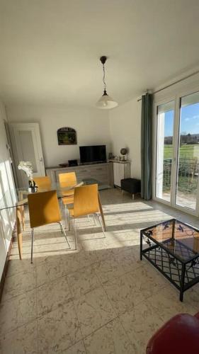 un salon avec une table en verre et des chaises dans l'établissement Maison 4 personnes dans village Cœur du perche avec toutes commodités Min 2 nuits, à Condé-sur-Huisne
