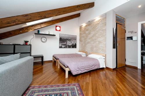 a bedroom with a bed and a couch in a room at STAGABIN La Mansarda Panoramica Un Rifugio di Eleganza e Tranquillità in Turin