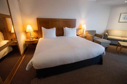 a hotel room with a large white bed and a chair at Crowne Plaza Brussels Airport by IHG in Zaventem