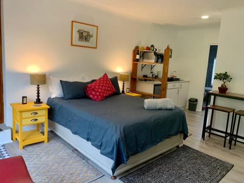 een slaapkamer met een bed met blauwe lakens en rode kussens bij Kindred Spirit Guest Suites with solar power in Knysna