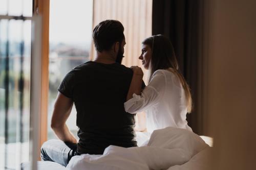 a man and woman sitting on a bed looking at each other at Hotel Der Heinrichshof in Lagundo