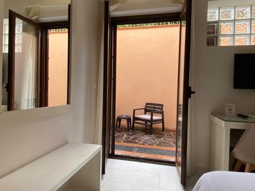 a bedroom with a door leading to a patio with a chair at Aether Suites Tropea - Free Private Parking in Tropea