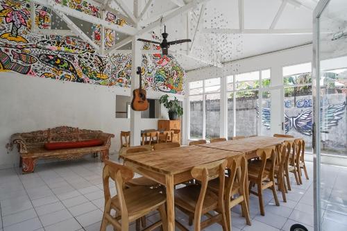 uma sala de jantar com uma mesa de madeira e cadeiras em Indopurejoy House - Komala Indah Cottages em Kuta