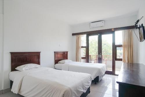 2 Betten in einem Zimmer mit Fenster in der Unterkunft Indopurejoy House - Komala Indah Cottages in Kuta